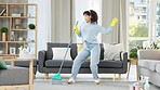 Woman dancing, singing and having fun while enjoying doing chores in the lounge alone at home. One black female sweeping, cleaning and doing housework while listening to music through headphones