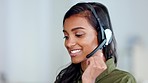 Happy female customer service agent smiling while working in a call centre and talking to a client with a headset. A helpful saleswoman assisting customers with purchase orders and questions online