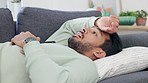 Upset, frustrated and sad young male lying, thinking and contemplating on a living room couch. Depressed man lounge on a sofa feeling unhappy, guilty and struggling with mental health indoors