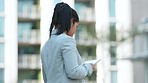 Businesswoman browsing on a digital tablet to monitor business progress, profit and loss while thinking alone outside. Serious corporate executive using technology to plan success or innovate ideas