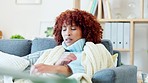 Sick woman with covid, flu or cold sneezing, coughing and blowing nose with tissue at home from fever or allergy. Ill lady with sinus in blanket on couch. Infected girl with afro feeling unwell. 