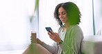 Relax, rest and carefree woman texting on a phone, drinking a healthy fruit. Happy female browsing social media or reading funny, meme or message online the internet and laugh while sitting on a sofa