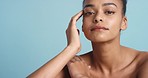 Black woman, skincare and beauty in luxury cosmetics relaxing against a blue studio background. Portrait of a African female model in healthy wellness touching smooth or tender skin in spa treatment