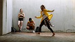 Black woman dancing to hip hop music, other dancer watch and then record her on phone for youtube video. Diverse dance group train together, friend watches young  woman move and practice choreography