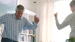 Happy senior couple dance in their living room together, acting silly and smiling in love while retired. Happily married healthy elderly people, having fun dancing in retirement and being goofy alone