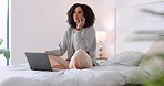 Young black woman talking on phone call, relax while working remote on laptop in bed. African American female enjoying casual chat in comfortable work from home space. Freelancer chilling in bedroom