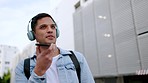 Headphones, phone call and city with young man talking in urban street for communication, podcast or internet. Conversation, music and happy male listening while speaking into mobile