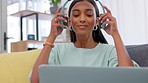 Freelance woman, blogger and laptop while wearing headphones to listen to podcast, music or do a video call conference while sitting at home. Indian woman influencer writing social media content