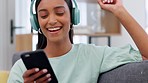 Woman, music playlist and phone to dance, listen or sing to radio media on headphones in home living room. Happy Indian person with smile, social media mobile and relax podcast on house interior sofa