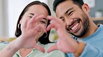 Happy, couple and love with heart and hands in romantic relationship gesture together at home. Man and woman in happiness in romance with hand shape in care and support with smile and laughing in joy