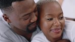 Love, care and happy black couple hugging while relaxing in bed in the bedroom at their home. Man kissing his woman on her head while bonding, resting and embracing each other at their house.