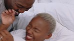 Happy, playful black couple and love in bed with a smile in their bedroom, room or home. Love, carefree intimate man and woman together in happiness, romance or bonding having fun in the morning.
