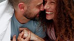 Happy couple, love and care together in bed under sheets, smiling and joyful bonding in happiness at home. Man and woman smile and laugh in sweet playful relationship romance or bond in the bedroom