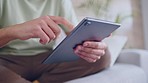 Social media, streaming and online entertainment on a digital tablet by a man relax on a sofa at home. Closeup of male hands browsing the internet, reading news or looking at a new subscription deal