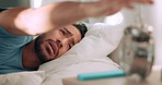 Man tired in bed with alarm time clock to wake up from sleeping in house or home bedroom on spring or summer morning. Sleepy, lazy and young Mexico person or Mexican hit snooze button on alarm clock