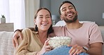 Happy couple, eating popcorn and watch a funny movie in the living room of their home or house. Love, romance and cheerful man and woman streaming comedy while watching at tv together on the sofa