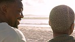 Black couple, love and laugh at a beach while watching the sunset and talking about a funny joke during a romantic moment. Happy man and woman having fun on picnic date or summer holiday vacation
