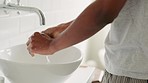 Man washing his hands with soap and water in the bathroom for protection from covid or germs. Black guy with a wellness, healthy and clean lifestyle cleaning for body care and hygiene at home.