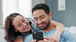Happy, love and a couple on a phone, kiss and streaming a online with social media or funny meme. Married asian woman and man relax on home living room sofa watching content on the web or internet