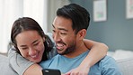 Asian couple, phone or laughing in hug on sofa in house living room or home interior. Happy smile, comic or fun bond man or woman or playful boyfriend or girlfriend with mobile tech for internet game