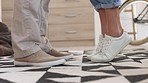 Couple, sneakers and closeup of adult feet with the woman on her tiptoe to kiss her boyfriend. Romance, love and husband standing with his wife in leather shoes in their home  having romantic moment.