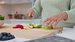 Woman makes healthy salad in the kitchen with apple, strawberry and banana for breakfast. People who live an active lifestyle eat organic fruit, vegetables and natural food for good nutrition or diet
