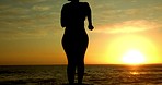 Fitness, freedom and silhouette with a sports woman running and celebrating on the beach at sunset. Workout, exercise and training with a female athlete celebrating a goal, target or health milestone