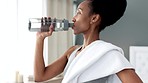 Water bottle, hydrate and thirsty fitness woman drinking after workout training or cardio exercise routine session in her living room home. Black woman drink fresh, cool and hydration h2o for health