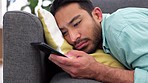 Bored, lonely and sad man with phone, social media and texting on home sofa lounge alone. Unhappy, depression and young guy waiting for mobile message and reading heartbreak notification in isolation