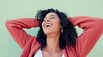 Freedom, hair and happy with a black woman playing with her curly hairstyle on a green wall background. Face, fun and smile with an attractive young female laughing with her hands in her curls