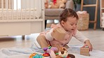 Baby, playing and toys for learning, mobility and early development with girl building educational toy blocks on floor at home. Infant child feeling curious and playful while on a blanket in nursery