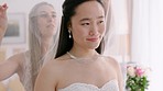 Asian bride and bridesmaid on day of wedding with a veil and happy, excited and smile on her face. Young woman in white dress ready to start marriage ceremony in a luxury hotel room with a friend