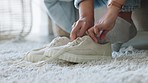 Woman get off bed to put on sneakers and tie shoelace together on bedroom carpet after a nap. Girl get off couch, sofa or chaise, after relax or sleeping, to put on shoes and fasten lace on rug