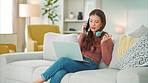 Girl, phone and call on sofa happy talking, headphones and smile, with laptop for online job in house. Woman, smartphone and conversation on couch, communication and computer for remote work in home