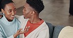 Black couple, laughing and kissing in sofa in house or home living room in love, trust or intimate safety. Smile, happy and talking man and woman bonding in relax communication or sharing comic joke