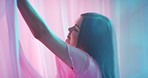 Woman, beauty and curtain model in neon light from Colombia with cosmetic makeup. Beautiful fantasy of young sensual female dancing between curtains enjoying playful dance in colorful pink background
