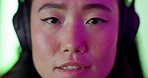 Woman, gamer and face with headphones in communication, talking or speaking online at home with neon lights. Closeup of asian female gaming streamer in conversation or advice with technology indoors