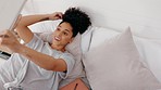 Black woman, relax and video call on tablet in the bedroom with smile for hair, communication and connection at home. Happy African American female relaxing on bed with touchscreen for social media