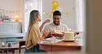 Couple, kiss and gift for birthday celebration, love and happy relationship together at home. Man and woman celebrating special day of birth in bonding happiness with cake and gifts at the table