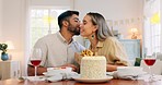 Interracial couple, gift and celebrate birthday being happy, kiss and smile in home at table with cake. Love, man and woman being content, romantic and present being cheerful celebration together.