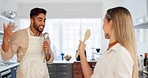 Singing, happy and dancing funny couple together in a kitchen at home enjoy their relationship and crazy together. Man and woman sharing playful dance, love and smile after cooking with apron in home