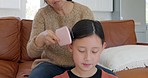 Mother, girl and brush hair for childcare, bonding and connect with haircare, natural beauty and relax together in living room. Mama, child and combs hairstyle, being loving or doing morning routine
