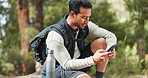 Nature hiking man, typing phone and sitting on rock for rest, break or relax with backpack outdoor. Forest adventure, woods explorer and smartphone for coordinate direction on gps navigation by trees