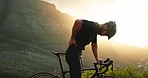 Back pain, muscle and injury of cycling man with mountain bike on nature journey with helmet or safety gear and outdoor sunset lens flare. Athlete cyclist with medical sports pain on hill and bicycle