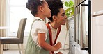 Cooking, mother and girl learning in the home kitchen to cook with mama and child family bonding. House, cooking food and quality time together of a mom and daughter looking at a stove baking