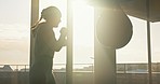 Boxing, energy and woman training with a punching bag for fitness, workout and cardio with a dark silhouette. Exercise, sports and athlete with power, strong and motivation as a boxer at the gym