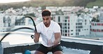 Fitness, exercise and battle ropes with a man on a rooftop for health, workout or endurance training in the city. Gym, sport and energy with a male athlete working out or exercising with heavy ropes