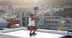 Squat, dumbbell and man fitness training on a rooftop for strong legs, powerful arms and healthy body. Energy, wellness and focused athlete lifting weights and squats in an exercise workout in a city