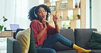 Black woman, music and phone while listening to headphones and singing while on living room sofa at home. Female rapper using free mobile streaming app for radio, audio or online playlist to relax 