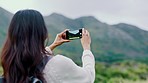 Photograph, nature and mountain with a woman using her phone while sightseeing during travel or vacation. Freedom, mountains and smartphone with a female traveler taking a picture of the wilderness